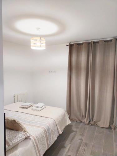 Cette chambre blanche comprend un lit et un rideau. dans l'établissement Maison de village, à Lasbordes