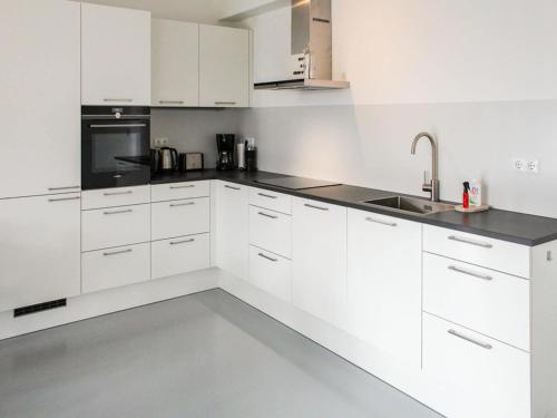 a white kitchen with white cabinets and a sink at Villa in Friesland with Jetty and Fenced Garden in Idskenhuizen