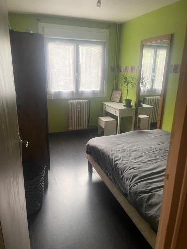 - une chambre avec des murs verts, un lit et un bureau dans l'établissement Appartement proche du centre - 58 m2, à Caen