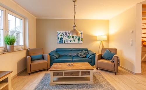 a living room with a blue couch and two chairs at Seewolf in Zingst