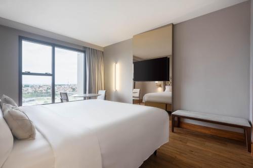 a hotel room with a large white bed and a window at Ouro Minas Hotel Belo Horizonte, Dolce by Wyndham in Belo Horizonte