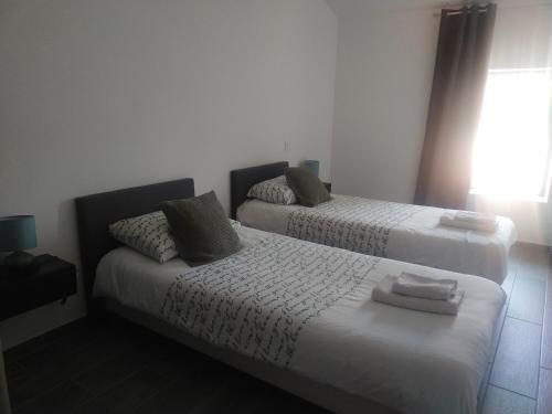 une chambre avec deux lits et une fenêtre dans l'établissement Maison, à Lasbordes