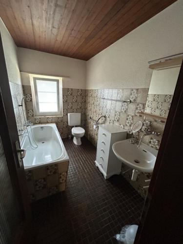 a bathroom with a tub and a sink and a toilet at Appartement dans joli village de campagne in Col des Rangiers