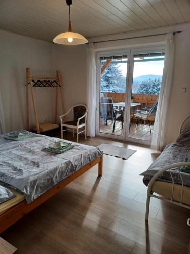a bedroom with a bed and a balcony with a table at Apartmány Šumava Boubín in Zátoň