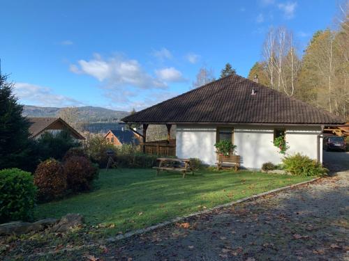 a white house with a bench in a yard at Apartmány Šumava Boubín in Zátoň