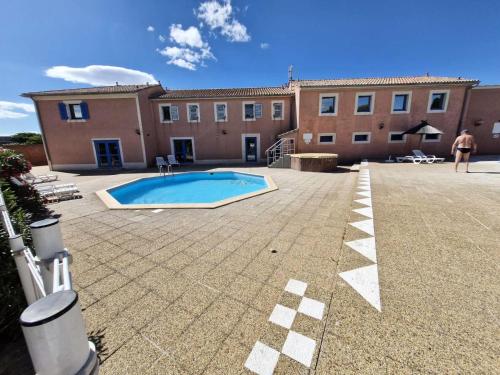 un homme debout en face d'un bâtiment avec piscine dans l'établissement Résidence Marina Ile Des Pecheurs - VILLA 3 PIECES 4 couchages LE BARCARES MAE-5894, à Port-Leucate