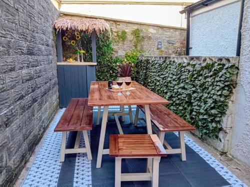 a wooden table and benches on a patio at Cosy Coastal Townhouse 10-Min-Drive to Beach in Bridgend