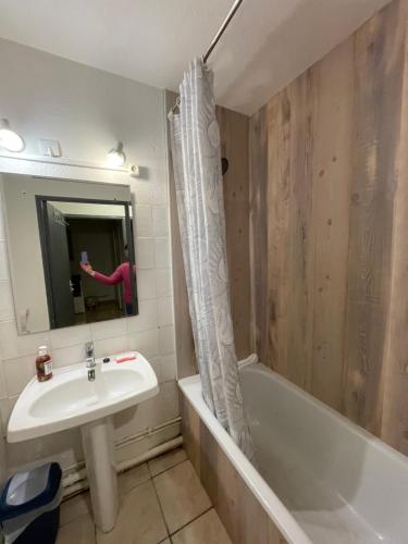une personne prenant une photo d'une salle de bains avec lavabo et baignoire dans l'établissement Narbonne centre T2 avec jardinet et parking, à Narbonne