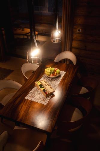 a wooden table with a plate of fruit and lights at Aurum Cabins in Zlatibor