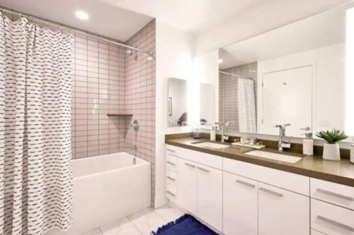 a white bathroom with a tub and a sink at Modern 3 Bedroom High-Rise with resort Pool in Los Angeles