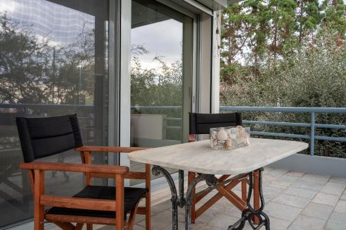 a table and chairs on a patio with a window at Athenian Riviera Seafront Residence in Saronida