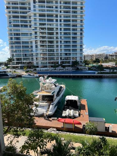 a boat is docked in a harbor with a large building at Marina Corazón Sea View - Condo Puerto Cancún in Cancún