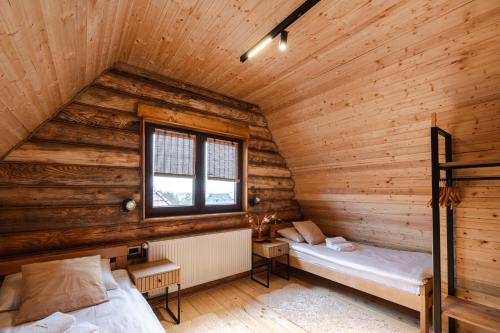 two beds in a room with wooden walls at Aurum Cabins in Zlatibor