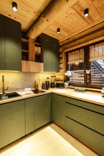 a kitchen with green cabinets and a wooden ceiling at Aurum Cabins in Zlatibor