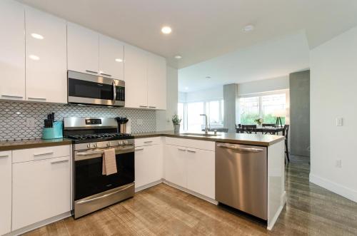 a kitchen with white cabinets and a stove top oven at Stunning 3 Bedroom High-Rise with Pool, Spa, and Rooftop Views in Los Angeles