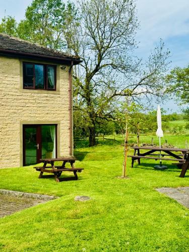 a building with two picnic tables in the grass at The Old Stone Trough Country Hotel in Kelbrook