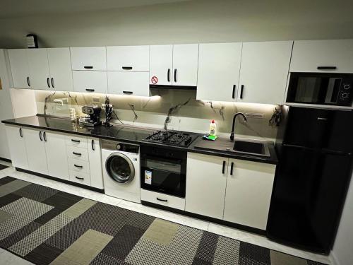 a kitchen with white cabinets and a black refrigerator at Apartament cu 2 Dormitoare de lux situat in complex ApartHotel Botosani 1 in Botoşani