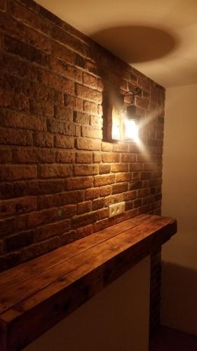 a light on a brick wall with a wooden counter at Ferienwohnung Uferweg in Fischbachau