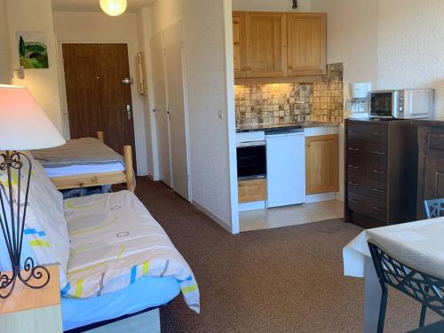 Cette chambre comprend une cuisine avec un lit et une table. dans l'établissement Charmant studio à Autrans, proche pistes et village, balcon sud, parking privé, accepte animaux - FR-1-737-33, à Autrans