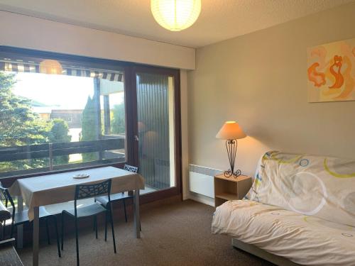 une chambre avec un lit, une table et une fenêtre dans l'établissement Charmant studio à Autrans, proche pistes et village, balcon sud, parking privé, accepte animaux - FR-1-737-33, à Autrans