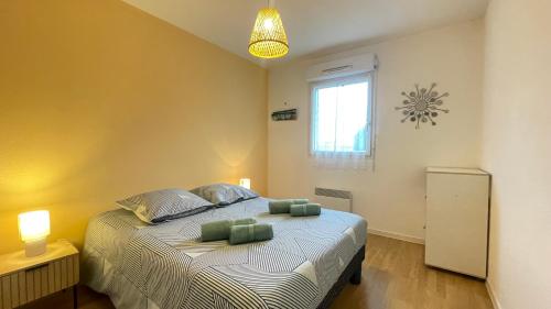 une chambre avec un lit avec deux oreillers verts dessus dans l'établissement Confort & Balcon,Cœur de Biscarrosse !, à Biscarrosse