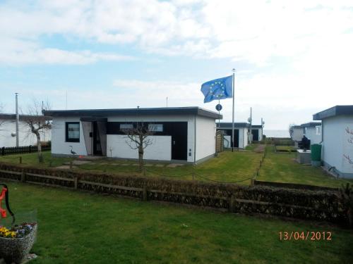 a small white house with a flag in the yard at Bungalow am Südstrand Staberdorf mit Meerblick in Staberdorf