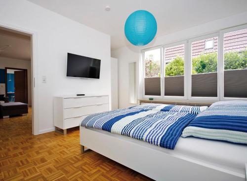 a bedroom with a bed and a tv and windows at Ferienwohnung "meerblau" in Fehmarn