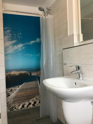 a bathroom with a shower curtain with a painting of a beach at FeWo Wiesenweg in Fehmarn