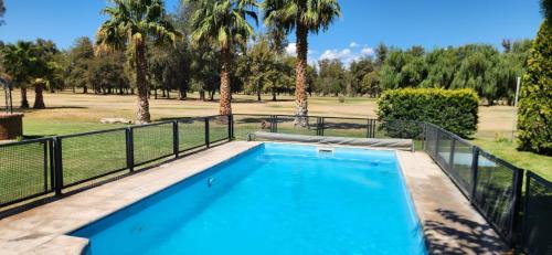 a swimming pool with a fence and palm trees at El Sauce, casa de campo & golf in Santa Lucía