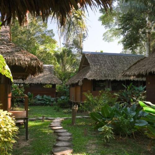 a house with a bench and a path in front of it at Ecolucerna Lodge Tambopata in Puerto Maldonado