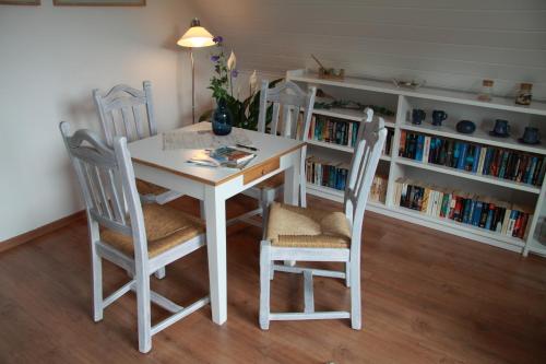 einen weißen Tisch und Stühle in einem Zimmer mit Bücherregalen in der Unterkunft Ferienwohnung weißes Haus in Meeschendorf
