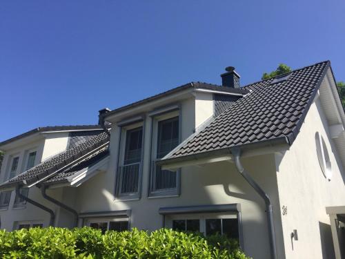 a white house with a black roof at Feriendoppelhaushälfte Böttcher in Meeschendorf