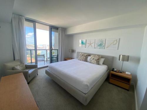 a bedroom with a white bed and a large window at Apt Miami Beach 1B1B with Kitchen Beach and Mall 2308 in Hallandale Beach