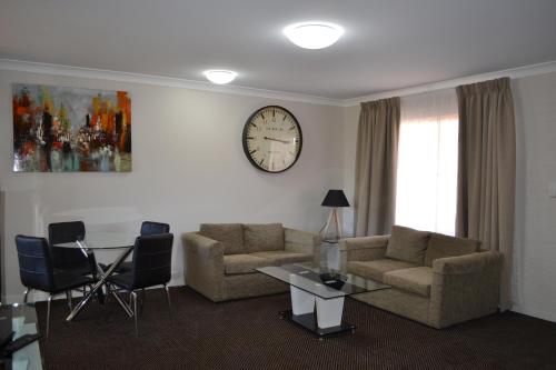 a living room with a couch and a clock on the wall at Cattlemans Country Motor Inn & Serviced Apartments in Dubbo