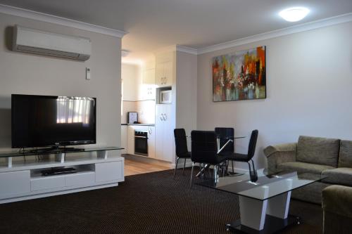 a living room with a couch and a tv at Cattlemans Country Motor Inn & Serviced Apartments in Dubbo