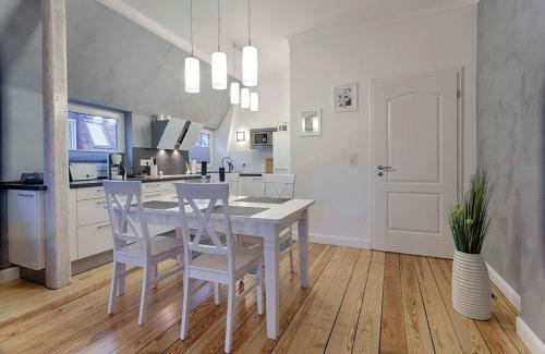 une cuisine blanche avec une table et des chaises dans l'établissement "Villa Anker" 1 Etage - rechts, à Fehmarn