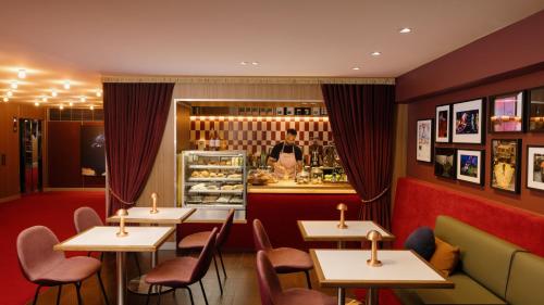 a restaurant with tables and chairs and a man behind the counter at Hotel Indigo Sydney Potts Point by IHG in Sydney