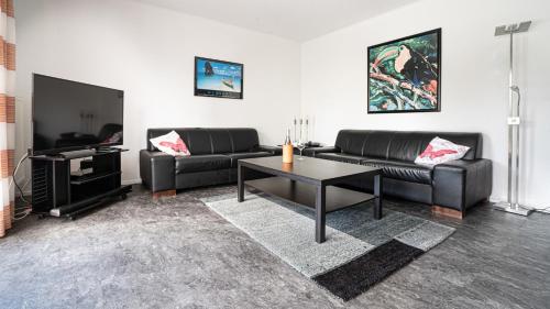 una sala de estar con 2 sofás negros y una mesa. en Haus Westwind Nr1, en Schlagsdorf