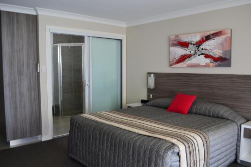 a bedroom with a large bed with a red pillow at Cattlemans Country Motor Inn & Serviced Apartments in Dubbo
