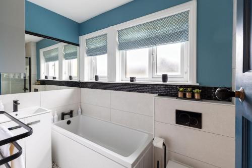 a bathroom with a tub and a sink and windows at The Kingsway in Ilkley