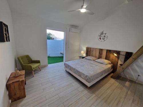 a bedroom with a bed and a green chair at Appartement au centre de Gosier 7 in Le Gosier