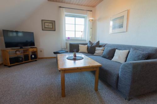 a living room with a blue couch and a coffee table at Ferienhof Böhnke Nr3 in Puttgarden