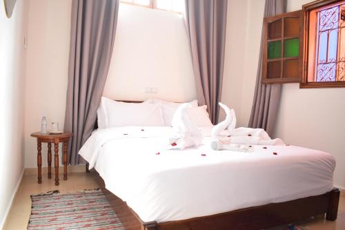 a bedroom with two beds with white sheets and a window at Maison Marrakech in Touggana