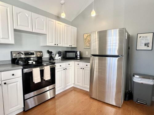 a kitchen with white cabinets and a stainless steel refrigerator at 3 BR Private Pondside View New Reno [Moose Lodge] in Bar Harbor