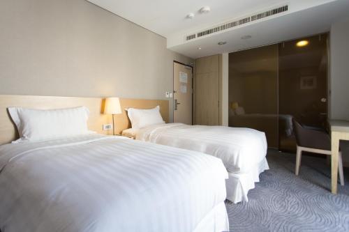 a hotel room with two beds and a desk at 麗馨商旅七賢館 in Kaohsiung