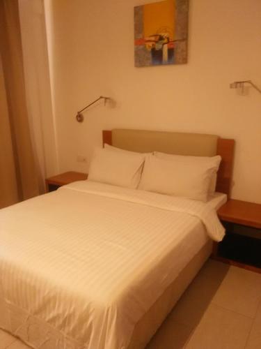a bed with white sheets and pillows in a room at Gloria Swiss Hotel & Apartment Sandakan in Sandakan