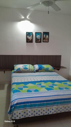 a bed in a room with three pictures on the wall at Lindo en el rodadero in Gaira