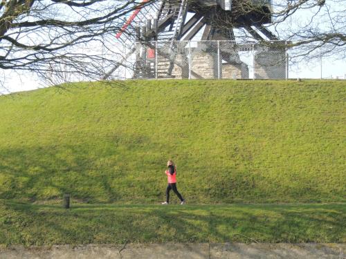 una donna che cammina davanti a una collina con un aquilone di B&B Stoega a Bruges