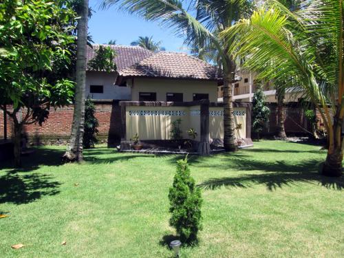 a yard with palm trees and a house at Yuli's Homestay in Kuta Lombok