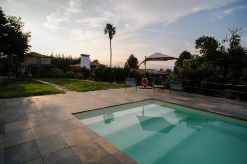 a swimming pool with two chairs and an umbrella at Quinta das Flores in Geraz do Lima